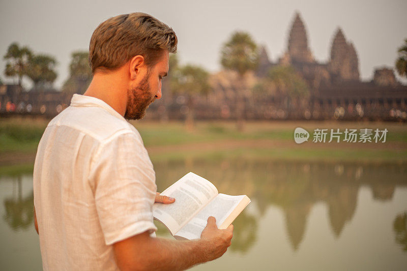 一个年轻人正在柬埔寨的古庙里阅读旅游指南