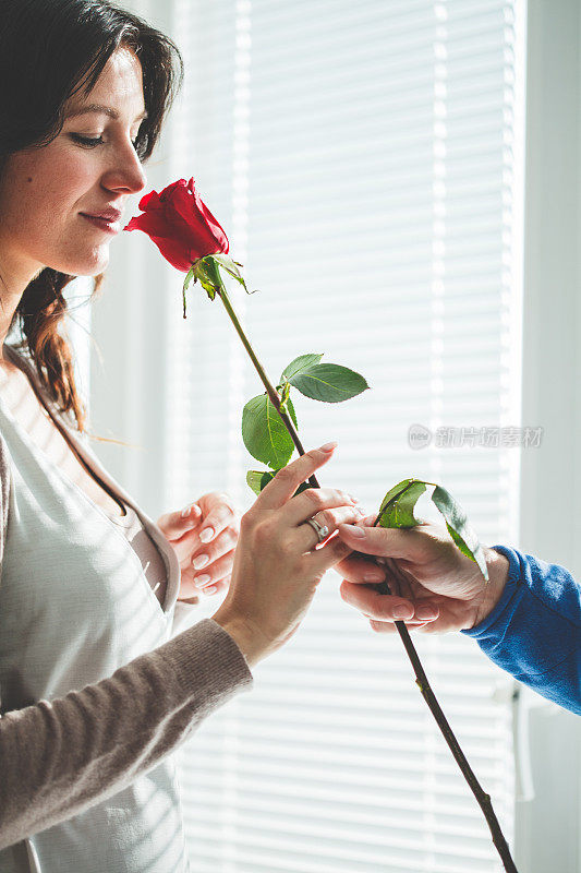 女人闻着男人手中的红玫瑰