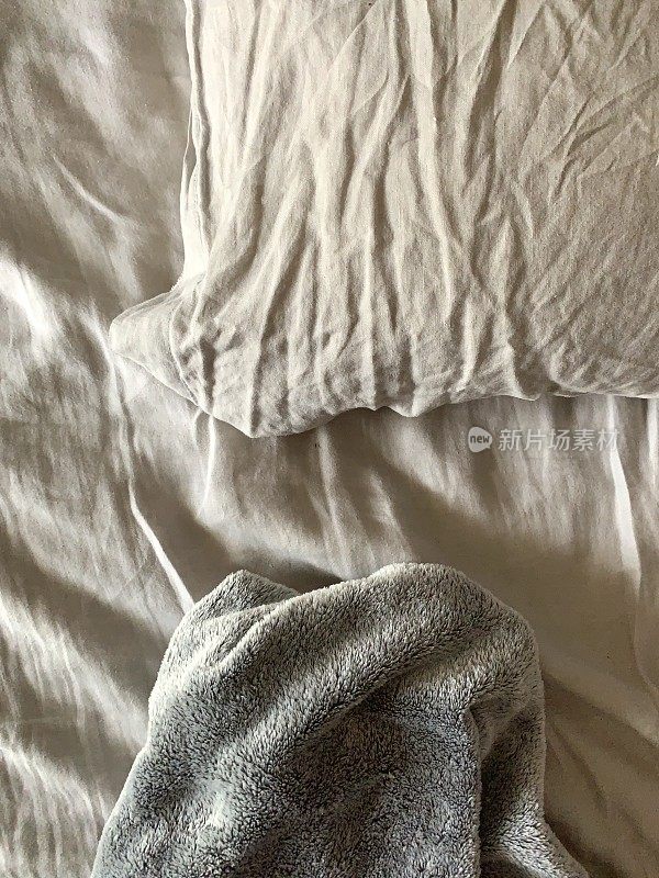 凌乱的床，枕头和羊毛毯子