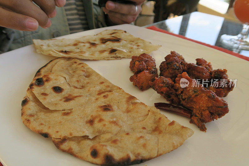 印度德里，印度男人在印度餐馆用餐，食物盛在盘子里，辣炸鸡肉炸丸子，大蒜馕饼，烤饼，肉配印度螺旋黄瓜和胡萝卜沙拉