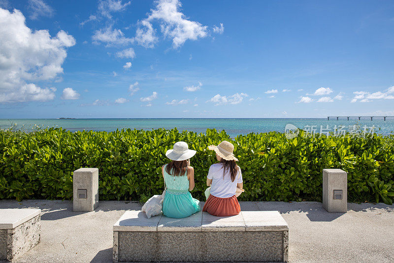 年轻女子坐在旅游胜地海滩的长椅上