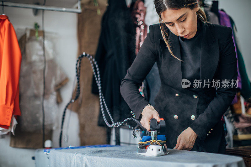 女时装设计师熨烫纺织材料在她的工作室