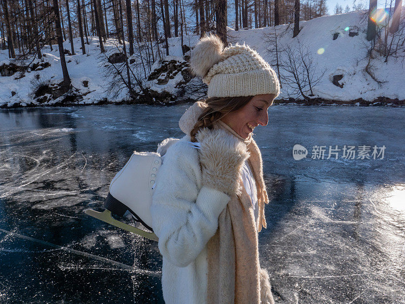 一个年轻女子肩上扛着冰鞋走在结冰的湖面上