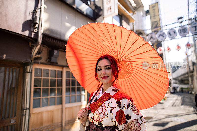 穿着和服的白人妇女走在传统的日本居酒屋巷子里