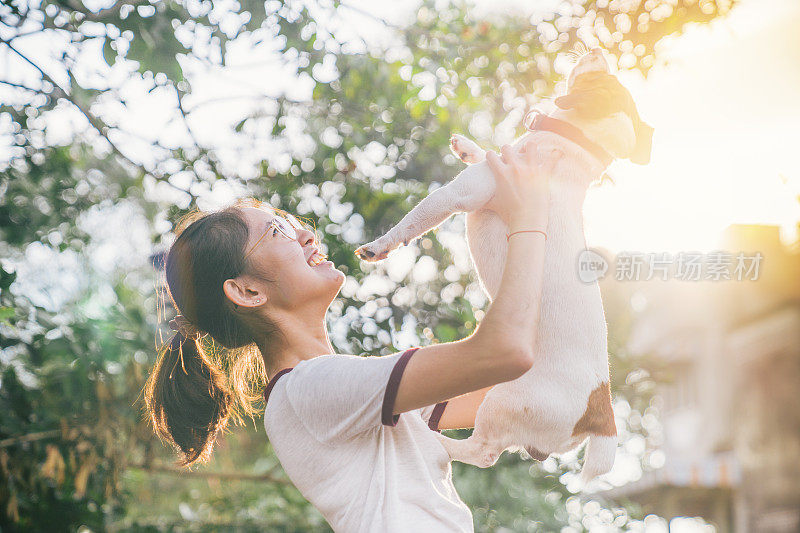 一个年轻的亚洲女孩和她可爱的宠物杰克罗素狗在夏天的公园里