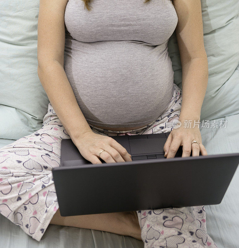 近距离观察孕妇在休产假期间在家用笔记本电脑工作
