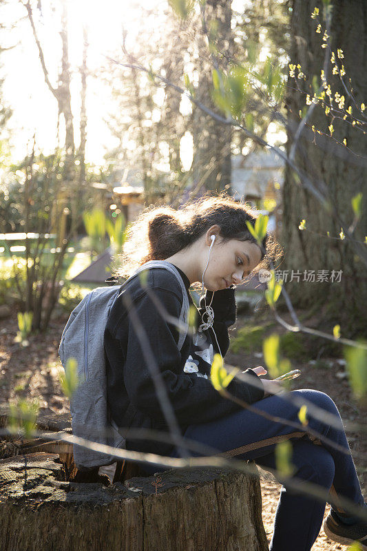 年轻女孩在花园里听音乐