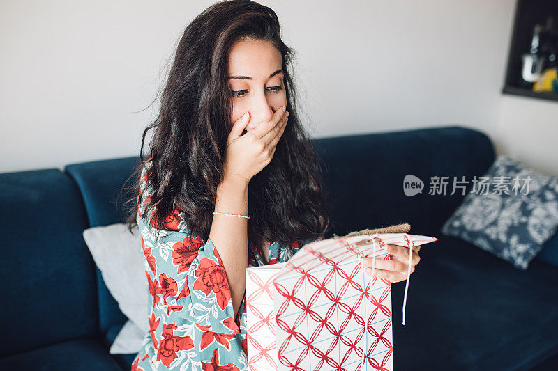 女人打开她的礼物，感到惊讶