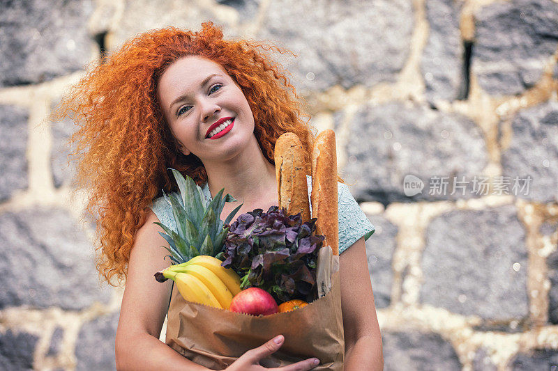 漂亮的年轻女人提着一个装满杂货的袋子