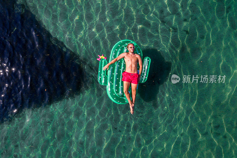 鸟瞰图上的人浮动在湖上与充气仙人掌日光浴