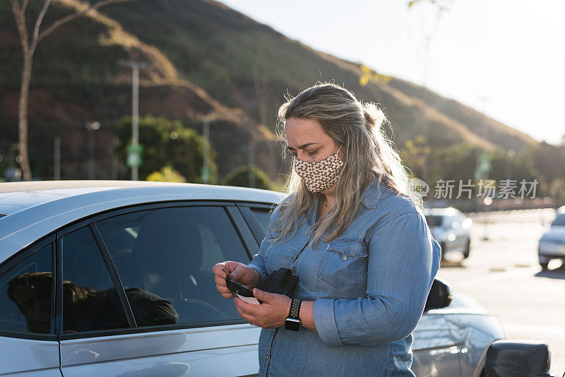 戴着防护口罩的妇女在超市停车场