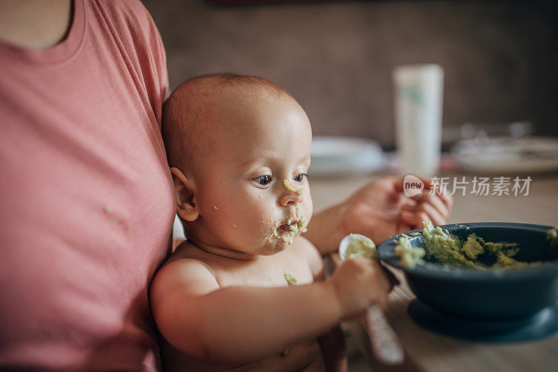 一位面目人非的母亲试图用勺子喂一个淘气的男婴