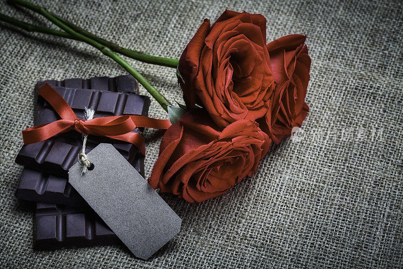 情人节主题:质朴的桌子上放着红玫瑰、巧克力棒和空白纸板