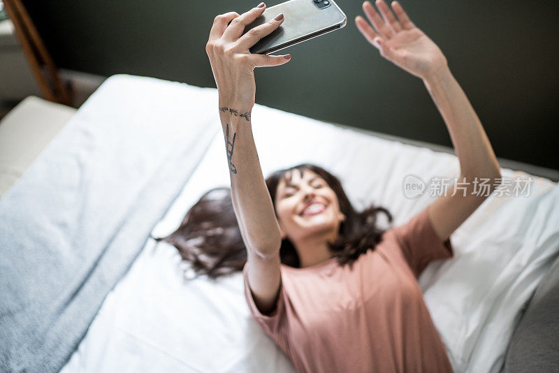 年轻女子在家里的床上拍摄自己