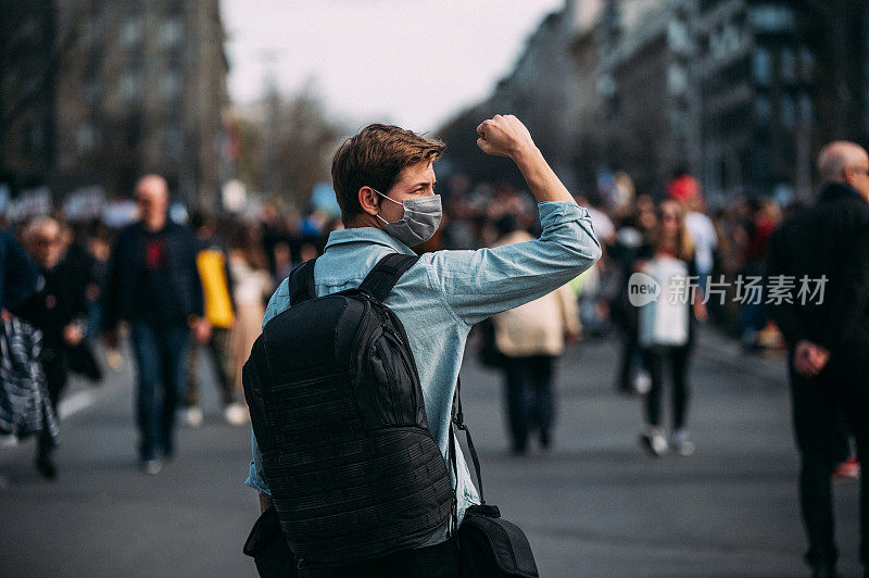 一名男性抗议者举起拳头的后视图