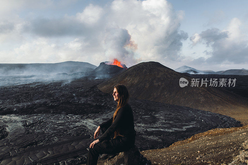 一名年轻的游客正在欣赏冰岛Fagradalsfjall火山喷发时熔化的熔岩的壮观景象