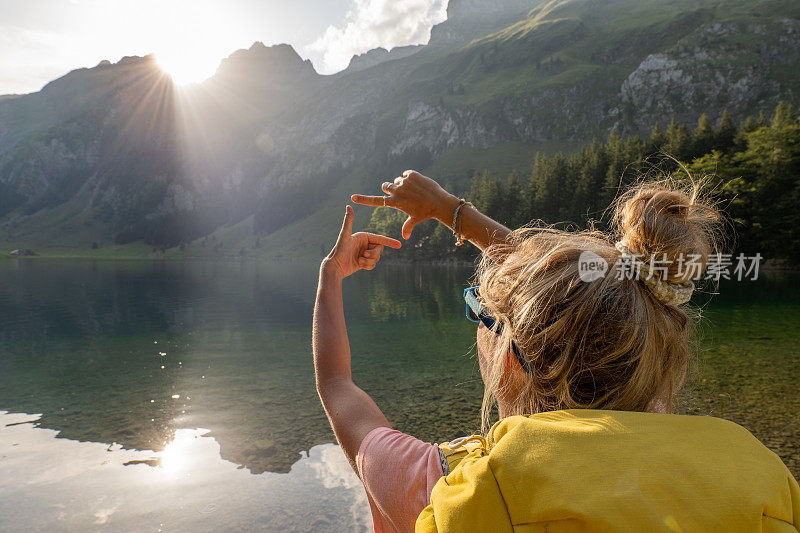 一名女性徒步旅行者在壮观的高山景观上做了一个手指框架来表达对环境概念的热爱