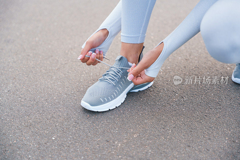 一个穿着白色运动服的年轻女子系鞋带的特写镜头