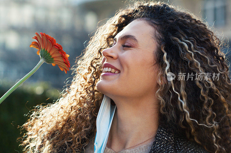 戴着面膜的年轻女子正在闻着花