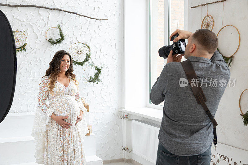 专业摄影师在摄影棚为怀孕的模特拍照。