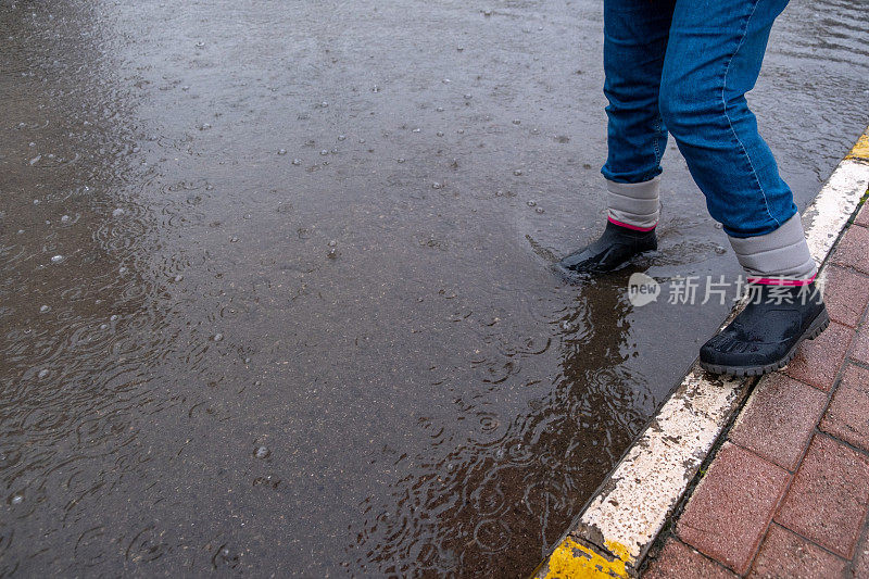 在室内天气，穿着近距离靴子的雨脚正踩在高水位的脚上。过马路。