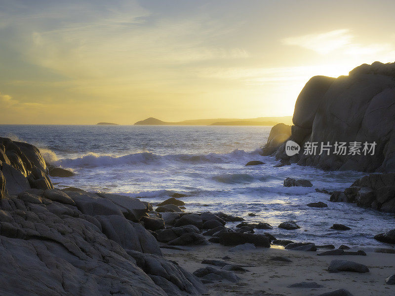 美丽柔和的日落在海滩岩层