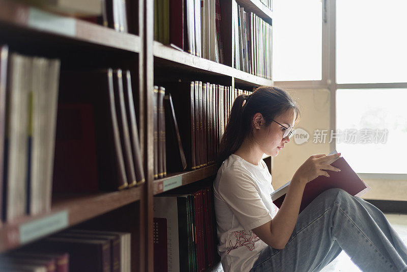 图书馆和教育理念，亚洲女性看书，倚在图书馆的书架上。