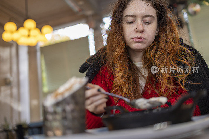 一个年轻的女人在路边的咖啡馆里享受她的晚餐。