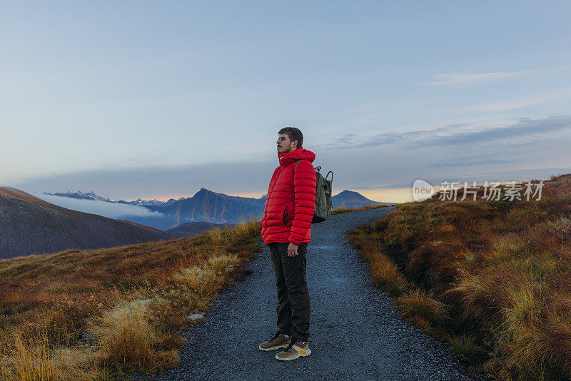 一个背着双肩包的男人在挪威的山上思考日落徒步旅行的侧视图