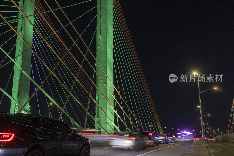 夜晚，绿色照明的科修斯科大桥上的交通堵塞。在高速公路上行驶的汽车的近距离夜景。长时间的曝光。视线水平，运动模糊