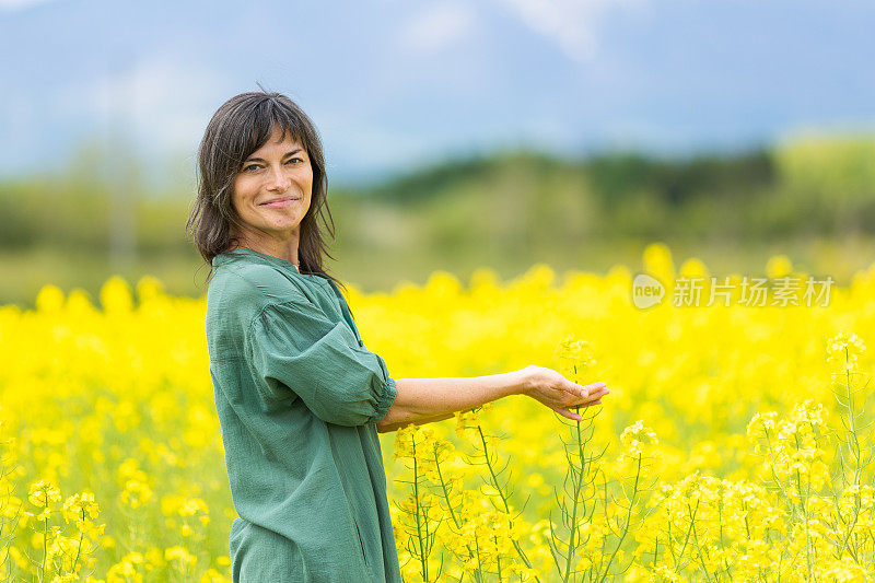 一位妇女在一片黄色的油菜花地里放松和享受户外活动