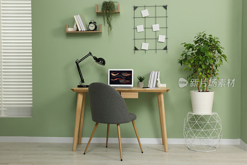 工作场所，现代笔记本电脑放在木桌上，家里有盆栽和舒适的椅子