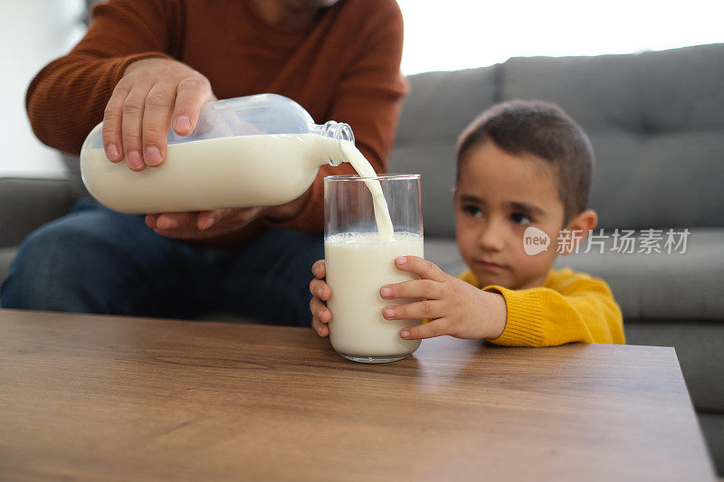 一个人把牛奶从罐子里倒进玻璃杯里