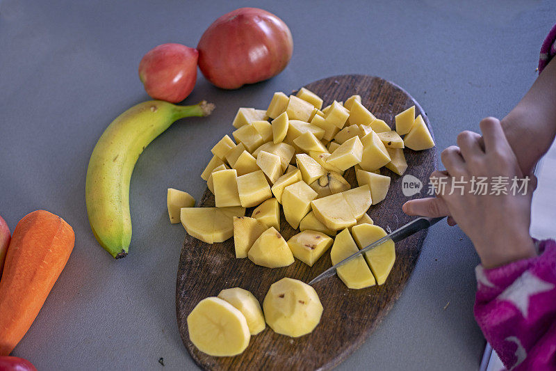 在砧板上用刀把土豆切成小块。flatlay