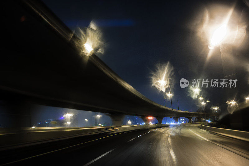 夜晚蜿蜒的道路在城市的灯光下。沿着佛罗里达州坦帕市的立交桥道路行驶。柔焦，长曝光