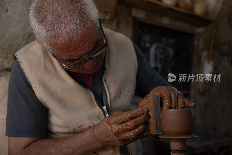 一位老人正在制作一个陶杯