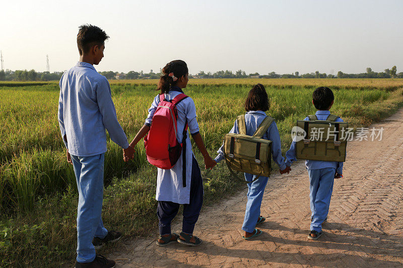 小学生放假后走在乡间小路上