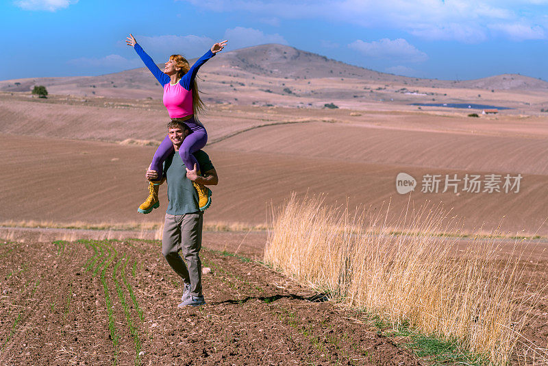 健康的生活方式:家庭野餐和锻炼。丈夫和妻子在耕地上玩耍。