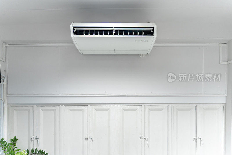 空调是白色的，呈矩形。它被安装在房间中央的天花板上。