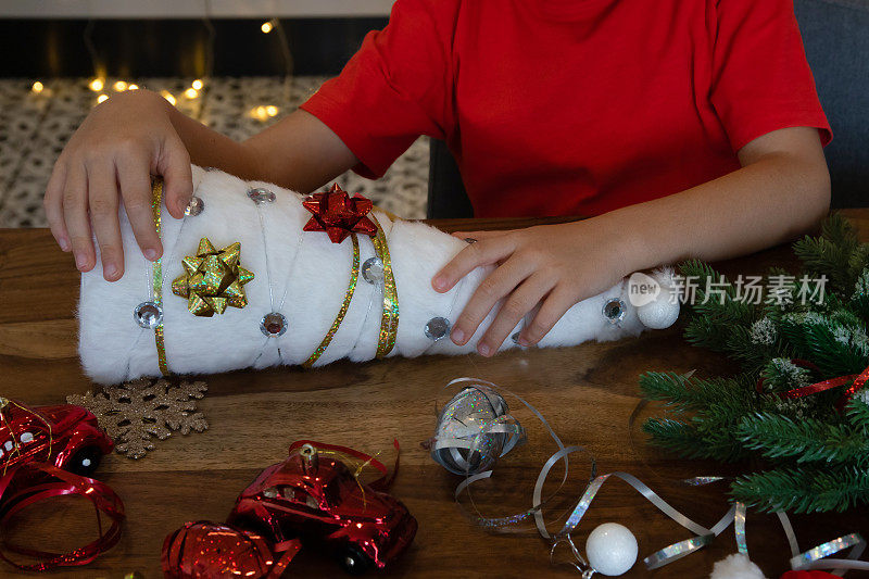 可爱的小男孩坐在桌子旁，自己动手做一棵白色的圣诞树。DIY。