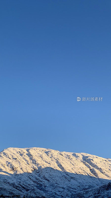 孤独地站着，山顶上覆盖着一层闪闪发光的雪。