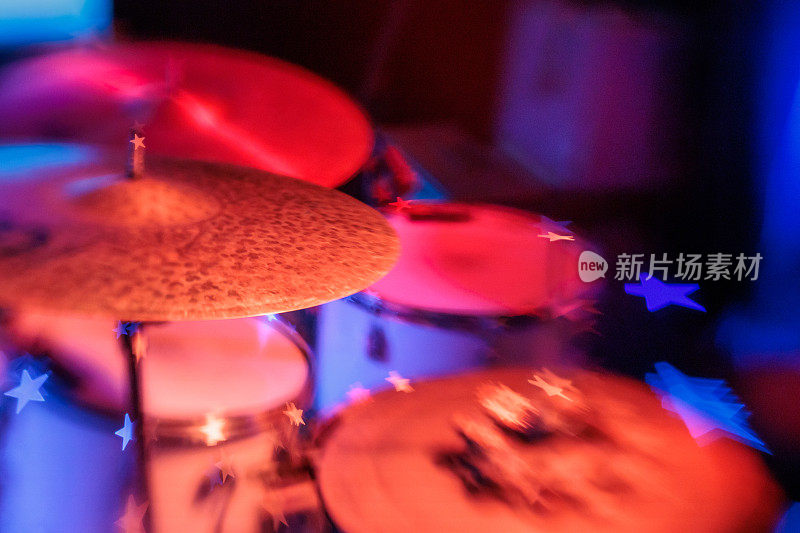 鼓套件铙钹在舞台上与充满活力的红色灯光和星形散景的特写