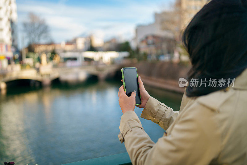 亚洲女人用手机拍照，在城里旅行。