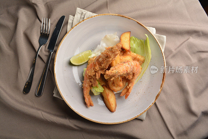 油炸酥脆虎虾和炸鱿鱼配炸薯条在盘子里棕色布桌西餐厅秘鲁菜咖啡馆清真菜单