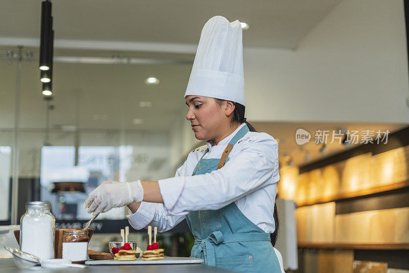 拉丁女职业厨师站在一家漂亮餐厅的厨房里准备美味的菜肴