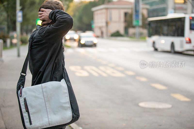 年轻男子与笔记本电脑袋等在公共汽车站-库存照片