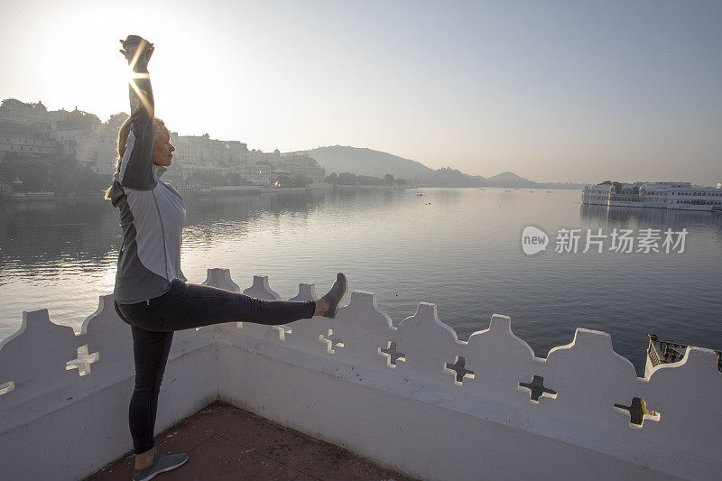 日出时分，一个成熟的女人在阳台上舒展着身体，眺望着湖面