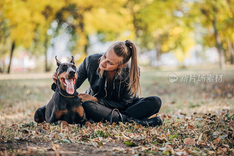 一个女人在公园里和她的杜宾犬玩耍