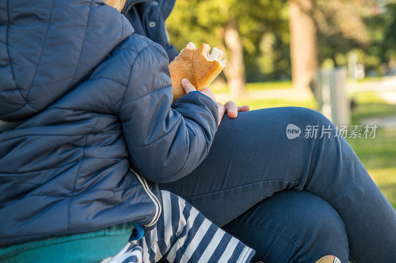一个男孩在斯洛文尼亚城市公园吃火腿三明治的特写，欧洲。尼康D850。