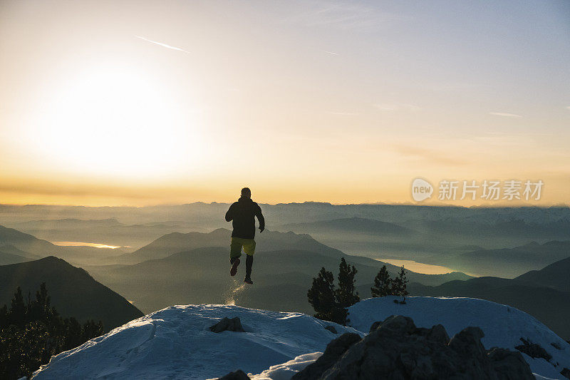 黎明时分，一名徒步运动员爬上雪山的山脊